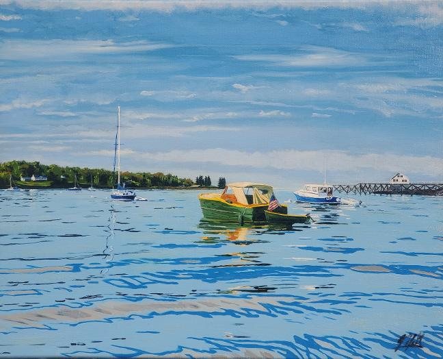 A green motorboat moored in a calm Maine harbor with a flag, dock, and sailboats beyond